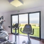 Fitnessraum mit Cardio-Geräten und Blick aufs Meer durch große Fenster.
