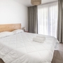 Helles Schlafzimmer mit Doppelbett und großen Fenstern in einer Ferienwohnung.