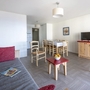 Helles Wohnzimmer mit Sofa, Esstisch, Stühlen und Fernseher.