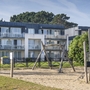 Apartmentgebäude mit Balkonen und einem Spielplatz im Vordergrund.