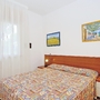 Helles Schlafzimmer mit Doppelbett, farbigem Bettbezug und zwei Nachttischlampen.