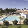 Außenansicht einer Ferienanlage mit Pool und Sonnenschirmen in ländlicher Umgebung.