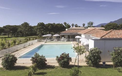 Außenansicht einer Ferienanlage mit Pool und Sonnenschirmen in ländlicher Umgebung.