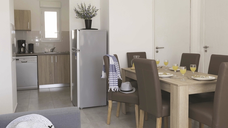 Essbereich und Küche in einer modernen Ferienwohnung mit Tisch, Stühlen und Kühlschrank.
