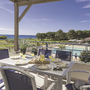 Terrasse mit Tisch, Stühlen, gedeckt für Frühstück, Meerblick, blauem Himmel.