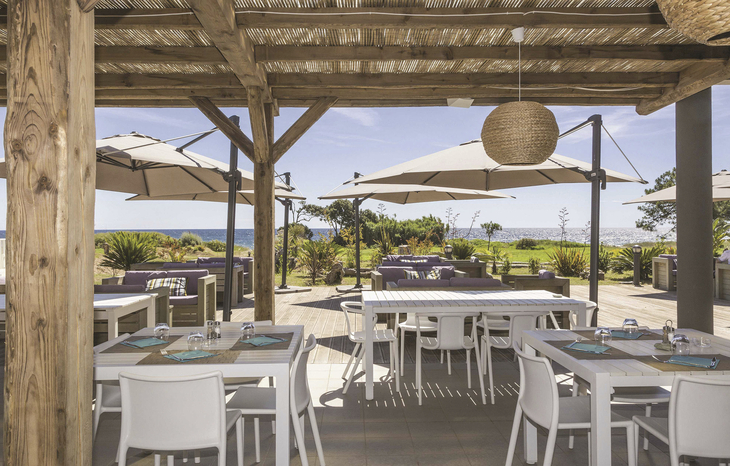Terrasse eines Restaurants mit Tischen und Blick aufs Meer.