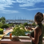 Frau auf Balkon mit Blick auf Hafen, bei sonnigem Wetter, Cap d'Agde.