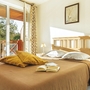 Helles Schlafzimmer mit Doppelbett, zwei Kissen und offenem Balkon.