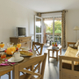 Wohnzimmer mit Frühstückstisch, Sofa, TV und offenem Balkon.