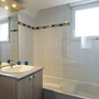 Helles Badezimmer mit Badewanne und Fenster.