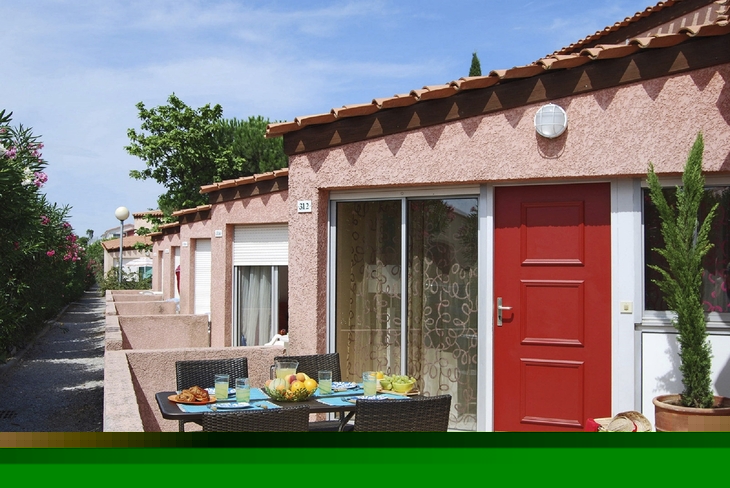 Reihenhaus mit Terrasse, Esstisch im Freien, rosa Wände, blauer Himmel.