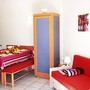 Essbereich in einer Ferienwohnung mit Tisch, Stühlen, rotem Sofa und Dekoration.