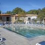 Poolbereich mit Liegestühlen in einer Ferienanlage bei Sonnenschein.