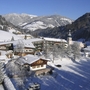 Verschneites Dorf in den Alpen mit Häusern und Kirche im Hintergrund.