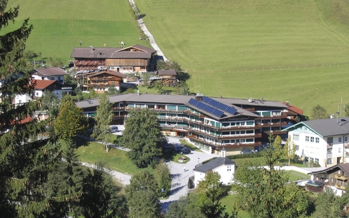 Luftaufnahme eines Chalet-komplexes mit mehreren Gebäuden in einer grünen Landschaft.