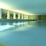 Innenpool mit großen Fenstern und hellgrünen Wänden in einer Appartementanlage.