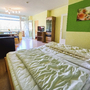Schlafzimmer mit Doppelbett, Sofa, Esstisch, Fernseher und großem Fenster in Appartement.