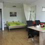 Modernes Appartement mit Doppelbett, Esstisch, Stühlen und heller Einrichtung.