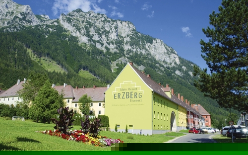 Außenansicht des Erzberg Alpin Resorts vor bewaldeten Bergen.