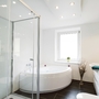 Moderner, heller Badezimmerbereich mit Eckbadewanne und Dusche.