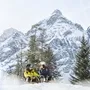 Zwei Personen rodeln im Schnee vor verschneitem Bergpanorama in Tirol.
