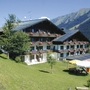 Hotelgebäude in alpiner Landschaft mit Balkonen und Sommerblumen.