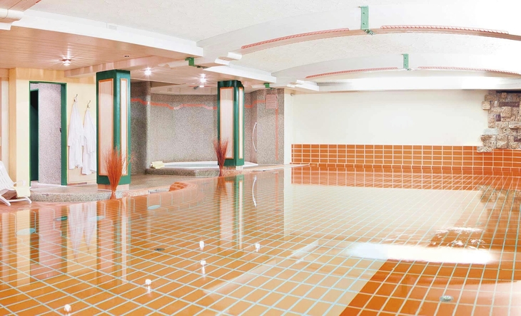 Hallenbad mit modernen Fliesen und heller Beleuchtung.