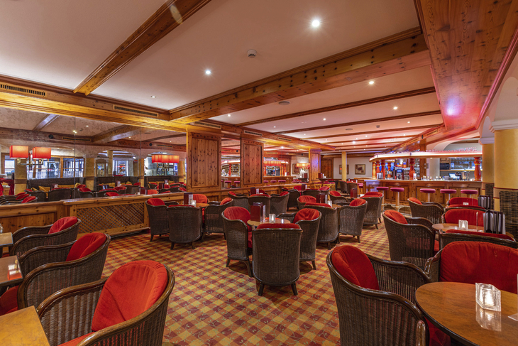 Hotelbar mit roten Sesseln und Holzelementen im IFA Hotel Alpenrose.