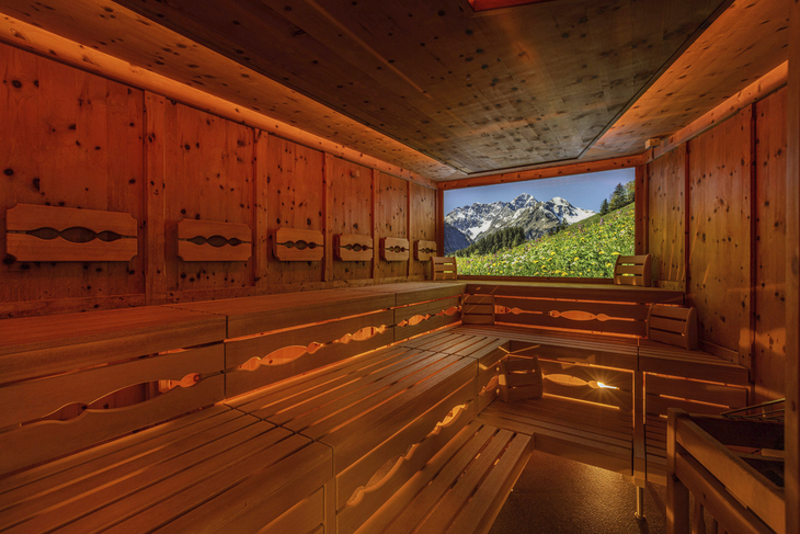 Sauna mit hölzernem Interieur und Berglandschaft im Fensterhintergrund