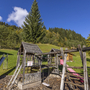 Spielplatz mit Rutsche und Klettergerüst, umgeben von Bäumen und Wiesen.
