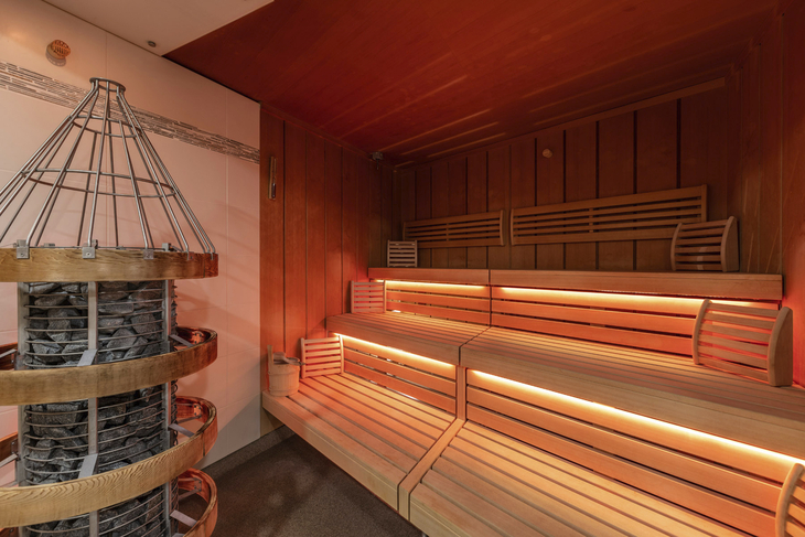 Innenansicht einer Sauna mit Holzverkleidung und Sitzbänken.