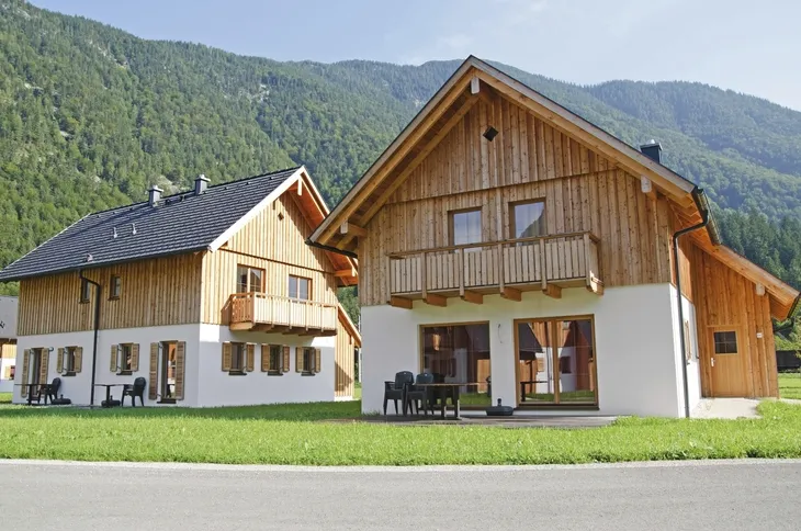 Zwei Holzhäuser vor bewaldetem Berg in Obertraun.