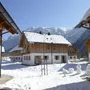 Schneebedeckte Chalets mit Bergen im Hintergrund bei sonnigem Wetter.