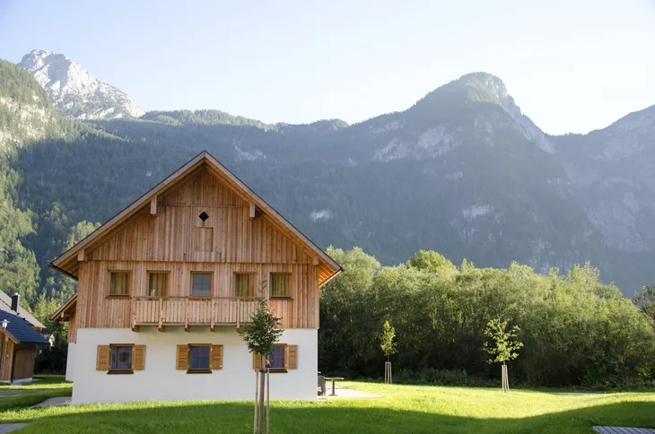 Holzhaus vor bewaldeten Bergen bei klarem Himmel.