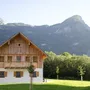 Holzhaus vor bewaldeten Bergen bei klarem Himmel.
