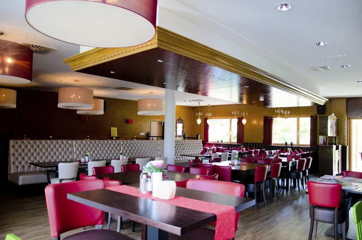 Restaurant mit roten Stühlen und eingedeckten Tischen.