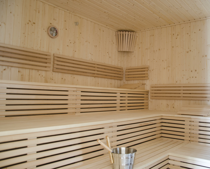 Leere Sauna mit Holzbänken und Eimer.
