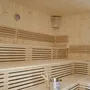 Leere Sauna mit Holzbänken und Eimer.