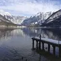 Landschaft mit See, schneebedeckten Bergen und einem Steg im Vordergrund.