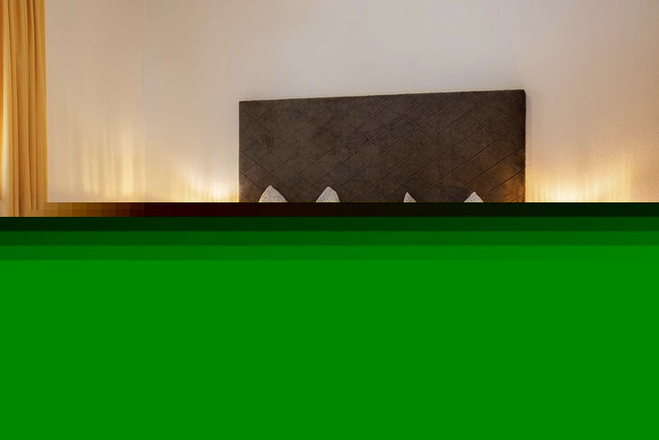 Doppelbett im gemütlichen Schlafzimmer mit Nachttischen und Lampen.