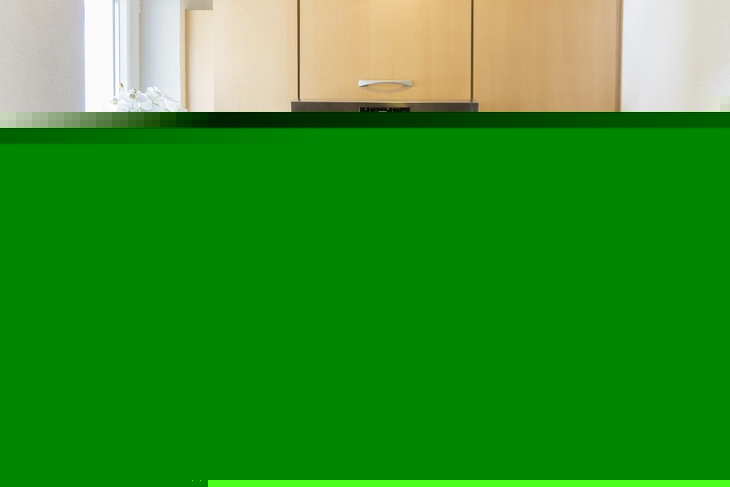 Kompakte Küche in einem Appartement mit Holzschränken und weißen Fliesen.