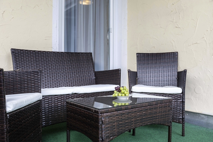 Gartenmöbel-Set mit Tisch und gefüllter Obstschale auf Teppich.