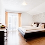 Helles Schlafzimmer mit großem Bett, Nachttischen und Fenster mit Vorhängen.