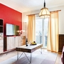 Wohnzimmer mit roter Wand, Sofa, Holzmöbeln und Fenster mit Vorhängen.