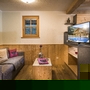Gemütliches Wohnzimmer in einer Ferienhütte mit Sofa, Holzmöbeln und Fernseher.