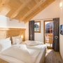 Holzverkleidetes Schlafzimmer mit Doppelbett und Balkonblick.