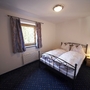 Schlafzimmer mit Doppelbett, Fenster und Nachtischlampe, gemütlich eingerichtet.