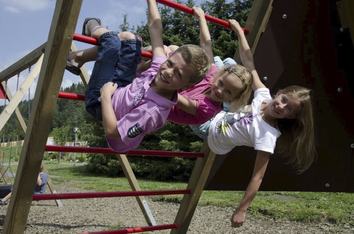 Kinder spielen lachend auf einem Klettergerüst im Freien.
