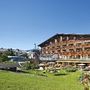 Sporthotel mit Holzfassade und Garten unter blauem Himmel