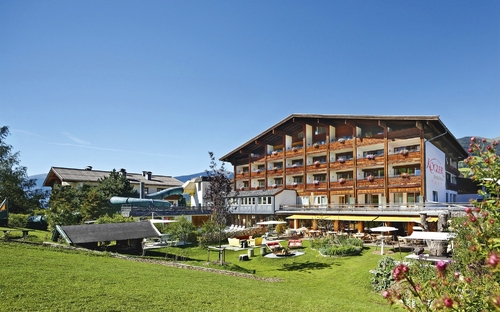 Sporthotel mit Holzfassade und Garten unter blauem Himmel